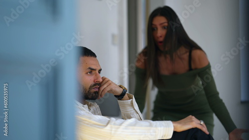 Woman wanting boyfriend attention. Girlfriend yelling at apathic boyfriend ignoring her screaming while seated on sofa. Candid couple in relationship crisis photo