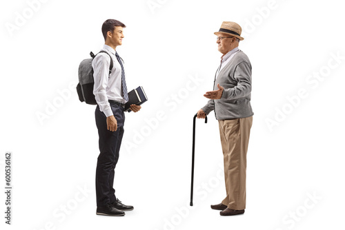 Full length profile shot of a grandfather talking to a male teenage student in a school uniform