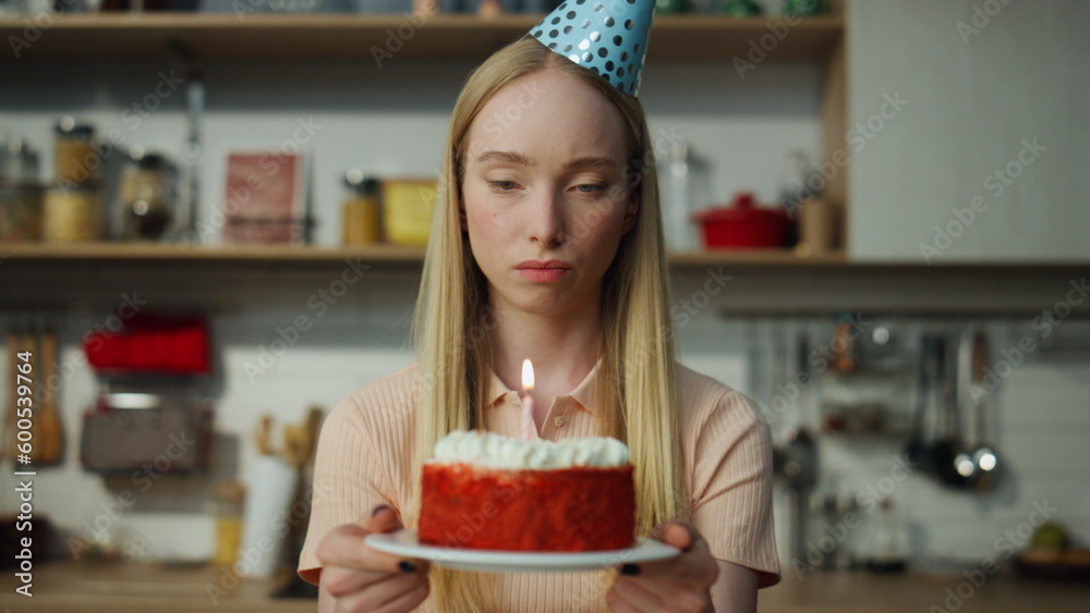 Unhappy woman celebrating birthday alone with cake looking in webcam close up.