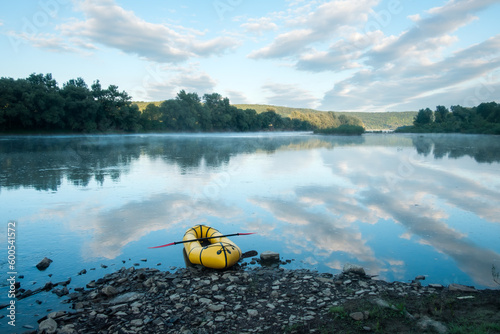 Yellow rubber boat packraft with red padle on beautiful sunrise river. Packrafting background. Active lifestile concept photo