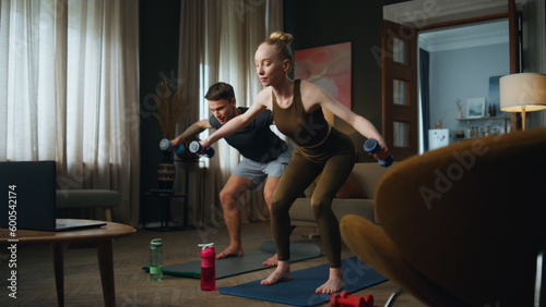 Fototapeta Naklejka Na Ścianę i Meble -  Family training dumbbells home. Couple making sport exercises for strong arms.