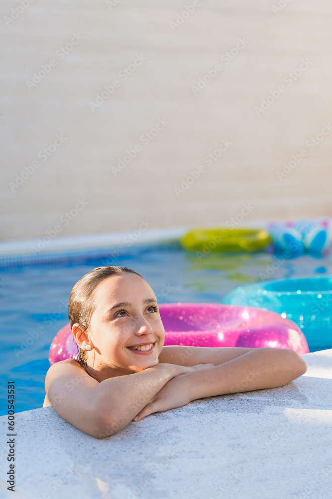 Smiling teenager girl at the edge of a swimming pool