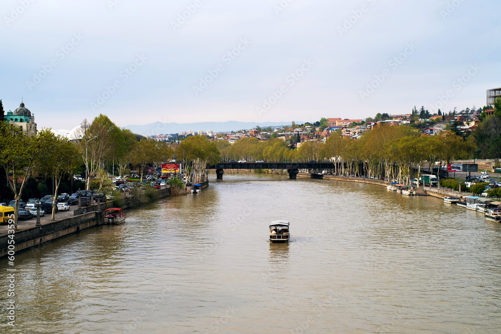 Pleasure boat floats on the Kura river in the center of Tbilisi in spring
