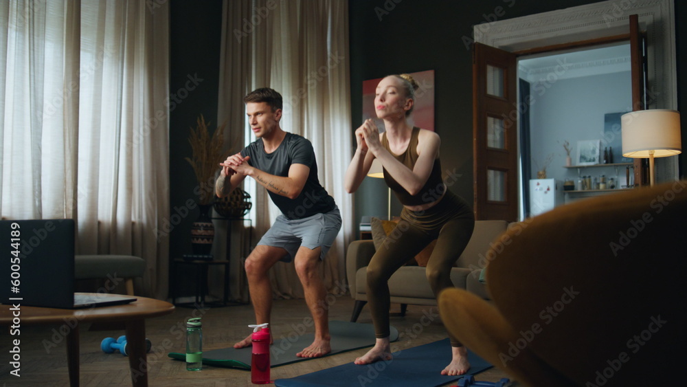 Couple squatting training together at home. Family workouting standing on mat. Couple squatting training together at home. Family workouting standing on mat.