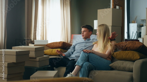 Couple talking new home interior discussing design sitting at comfortable couch.