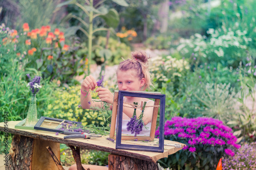 beautiful blond girl in floral garden holding wooden frames with purple lavender flowers © katarinagondova
