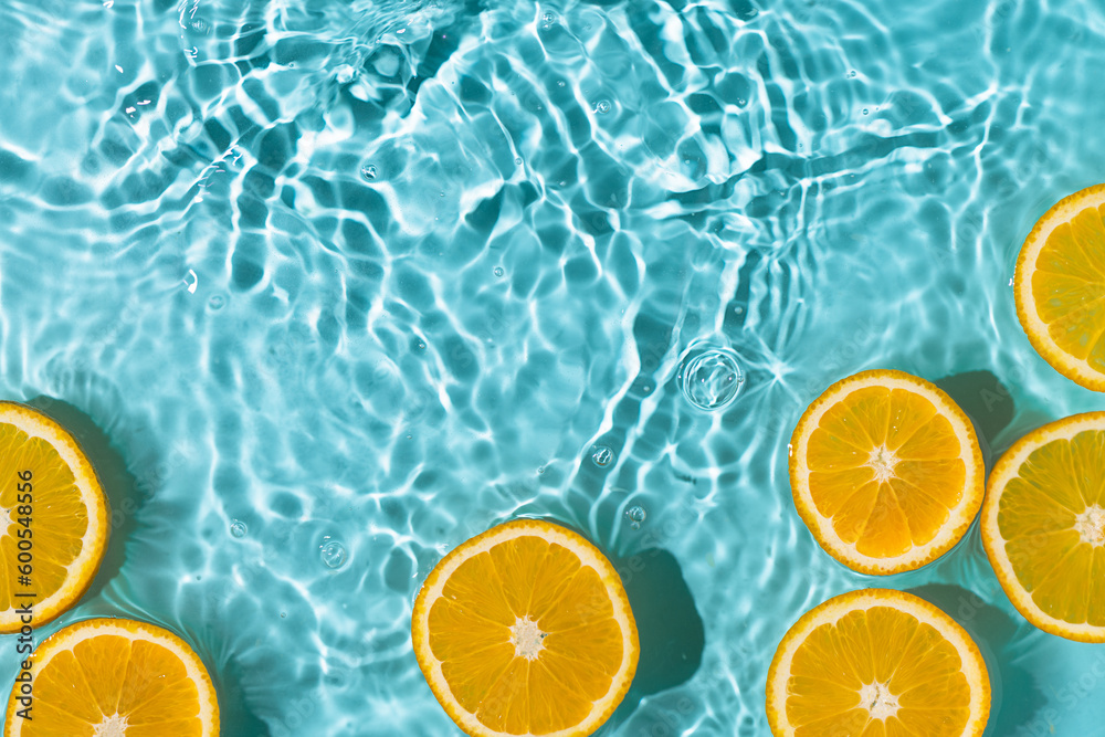 Creative summer background with orange fruit slices in swimming pool water. Summer wallpaper with copy space. - obrazy, fototapety, plakaty 