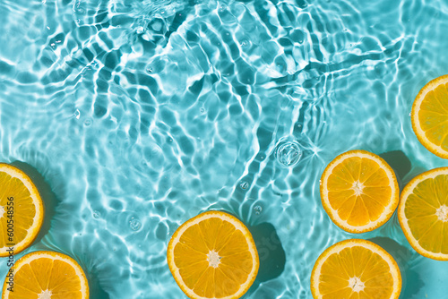 Fototapeta Naklejka Na Ścianę i Meble -  Creative summer background with orange fruit slices in swimming pool water. Summer wallpaper with copy space.