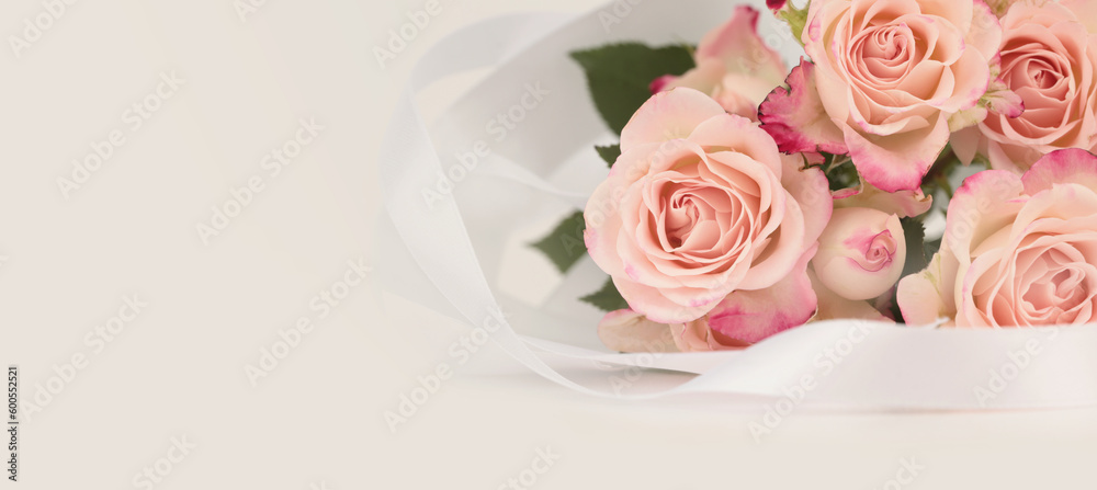 Pink rose flower bouquet with white silk ribbon. Light beige horozontal copy space background. Pink rose flower bouquet with white silk ribbon. Light beige horozontal copy space background.