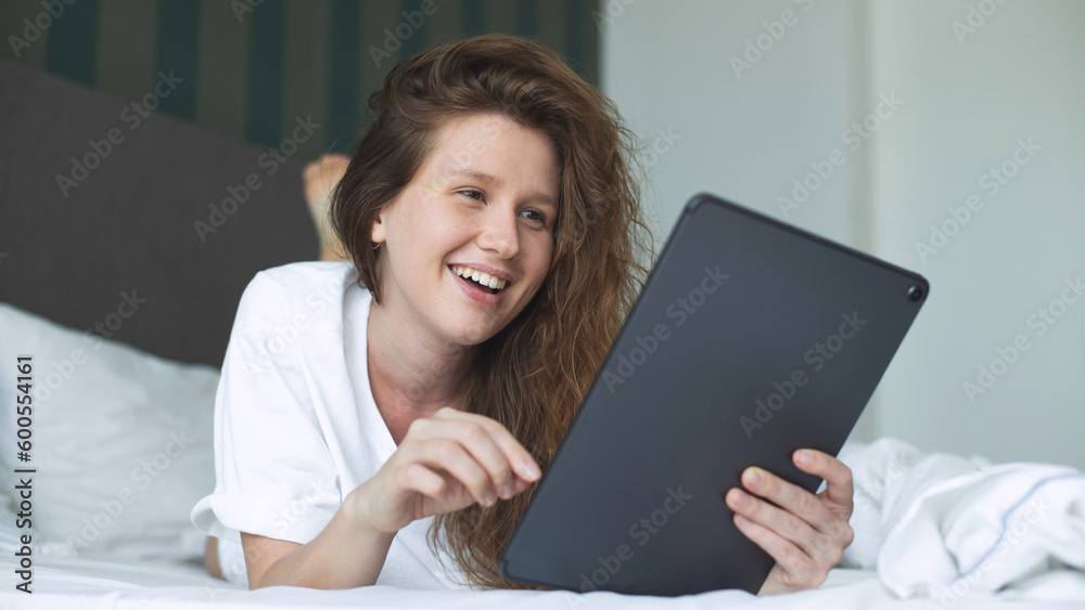 Happy young woman is using tablet computer at home in bed in bedroom, smile, have fun Happy young woman is using tablet computer at home in bed in bedroom, smile, have fun