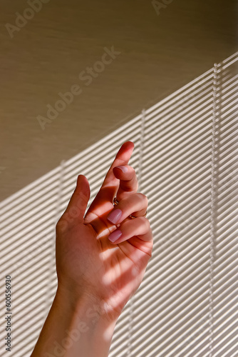 Female hand with pink nail polish in natural sunlight with shadows