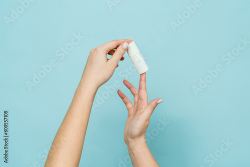 Bottle of nasal spray or eye drops in a female hand. Copy space