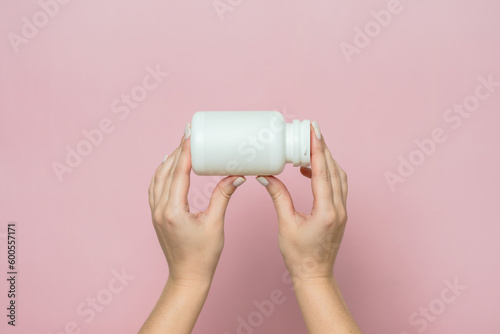 Bottle of pills or vitamins in woman's hand. Product branding mockup.