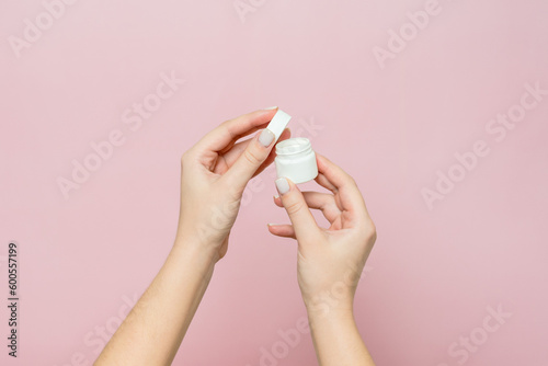 White jar or bottle with cream (ointment) in woman's hands. Facial care, bottle with cosmetic product