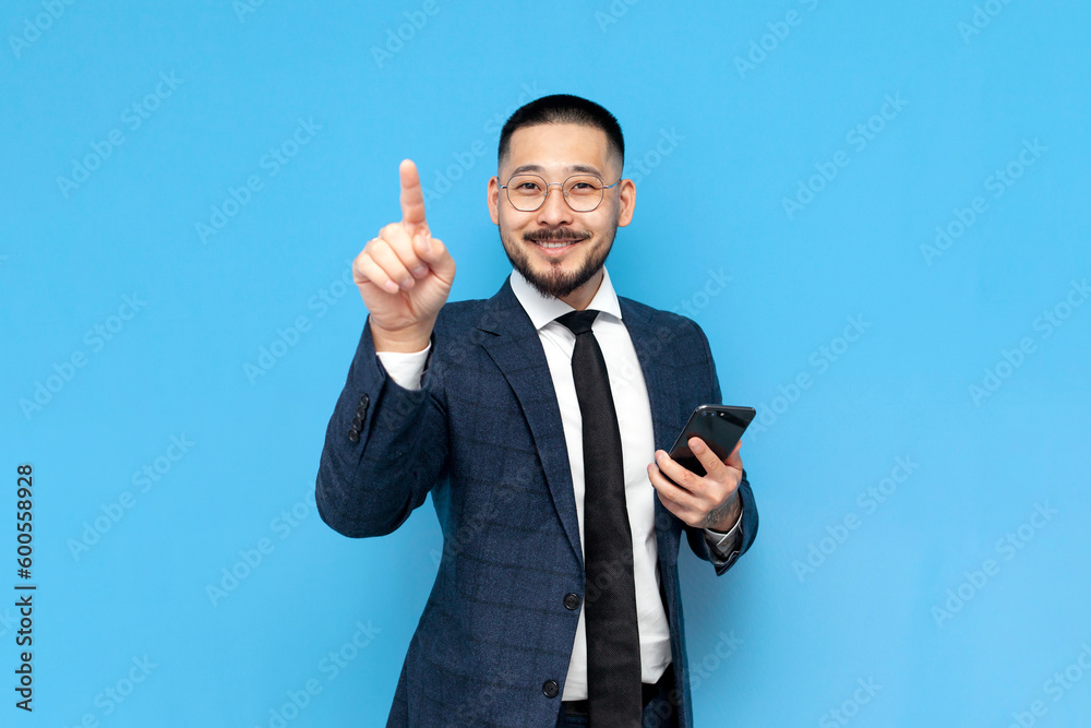 asian businessman in suit and glasses holds smartphone and presses with finger on an empty space asian businessman in suit and glasses holds smartphone and presses with finger on an empty space