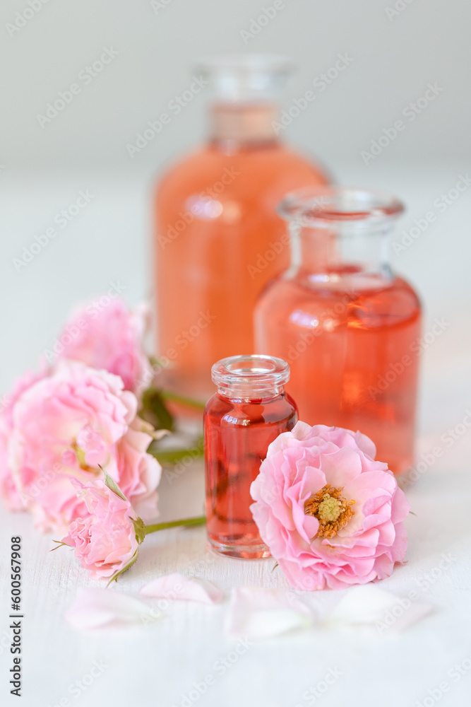 Concept of perfume with pure natural organic rose ingredient, essential oils. Glass bottles with flower herbal extract and elixir. Perfumery cosmetic toilet water fragrance, cream, skin care product Concept of perfume with pure natural organic rose ingredient, essential oils. Glass bottles with flower herbal extract and elixir. Perfumery cosmetic toilet water fragrance, cream, skin care product