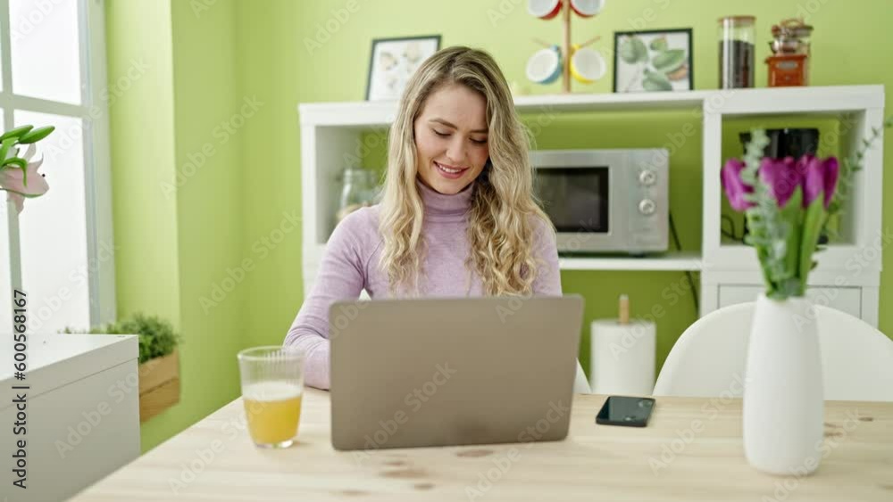 Young blonde woman using laptop and smartphone at dinning room Young blonde woman using laptop and smartphone at dinning room