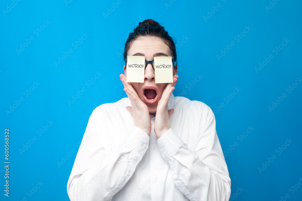shocked woman manager screaming on blue background, girl office worker with papers in front of her eyes surprised shocked woman manager screaming on blue background, girl office worker with papers in front of her eyes surprised
