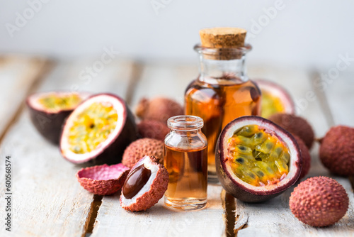 Glass bottles with pure organic essential litchi and passion fruit oil on wooden background. Concept of natural ingredients for beauty treatment, skin care, massage. Exotic fruits extract and essence