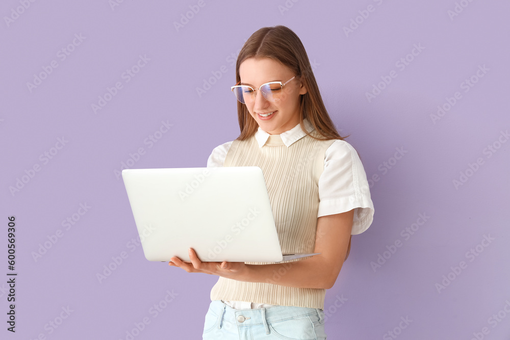 Female student studying with laptop on lilac background Female student studying with laptop on lilac background