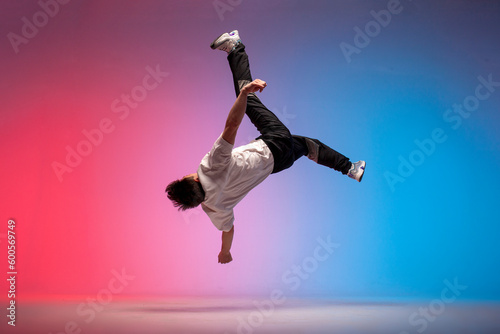Fototapeta guy acrobat doing back fat in new lighting, male dancer jumps and falls in the a