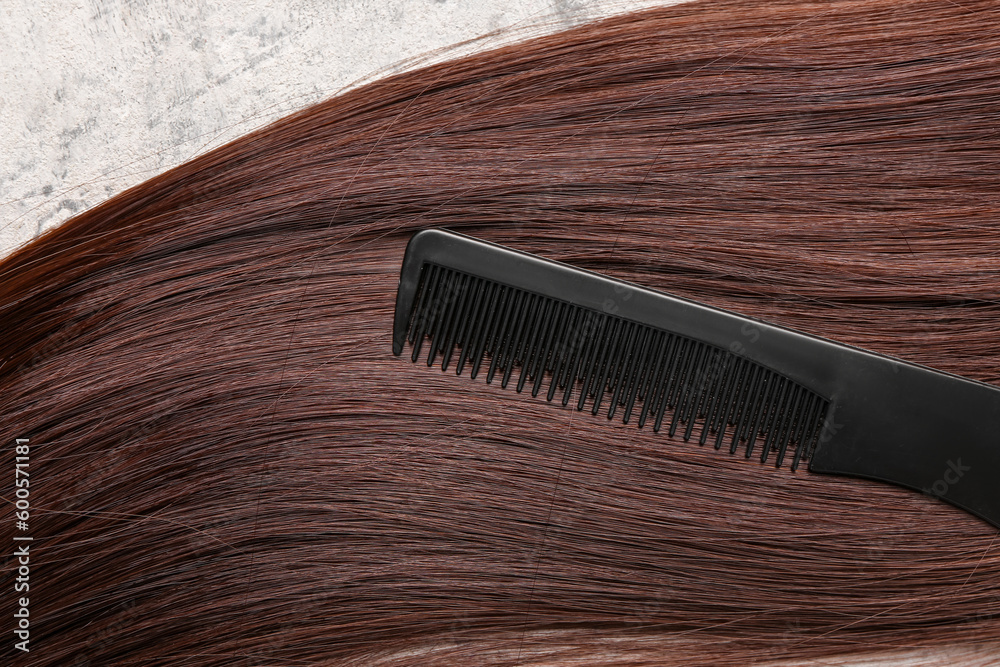 Obraz premium Brown hair with brush on grunge background, closeup
