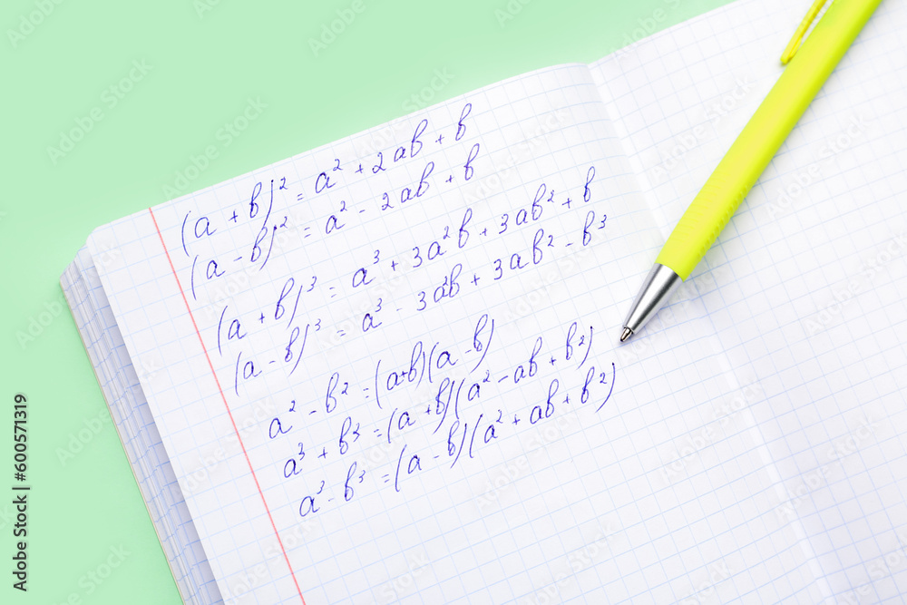 Copybook with maths formulas and pen on green background Copybook with maths formulas and pen on green background