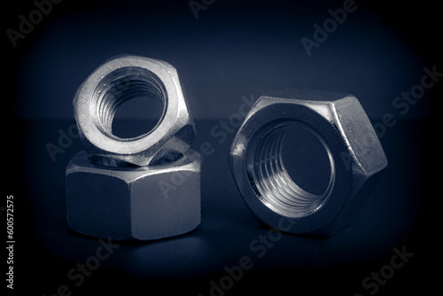 Metallic nuts. Low-key concept picture taken in studio with soft-box and dark background representing some mechanical components.