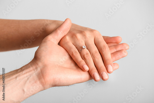 Engaged couple holding hands on light background  closeup