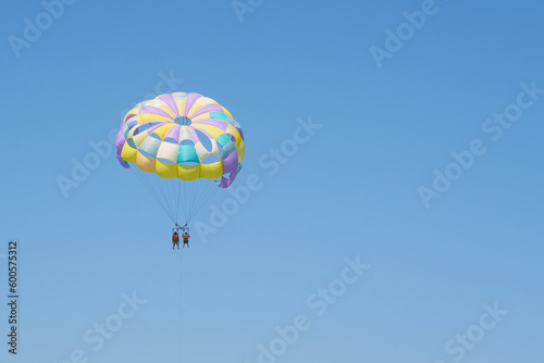 Colorful parasailing parachute against a clear blue sky.