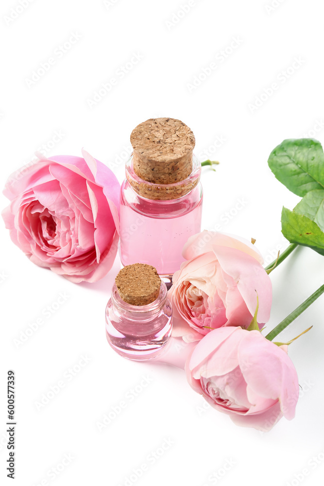 Bottles of cosmetic oil with rose extract and flowers on white background Bottles of cosmetic oil with rose extract and flowers on white background