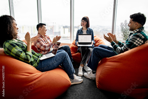 Schilderij op canvas Diverse group of professionals clapping hands while female expert feeling grateful with digital gadget in open office