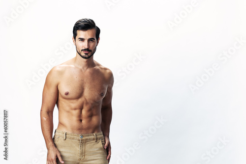 Man athlete model with a naked torso and six pack abs sporty inflated figure and tan on a white isolated background  fashionable clothing style  copy space  space for text