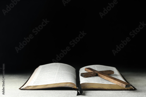 Holy Bible with wooden cross on dark background
