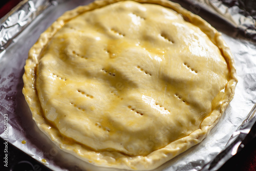 making a closed pie. Round raw pie on a baking sheet. Spread with chicken yolk.