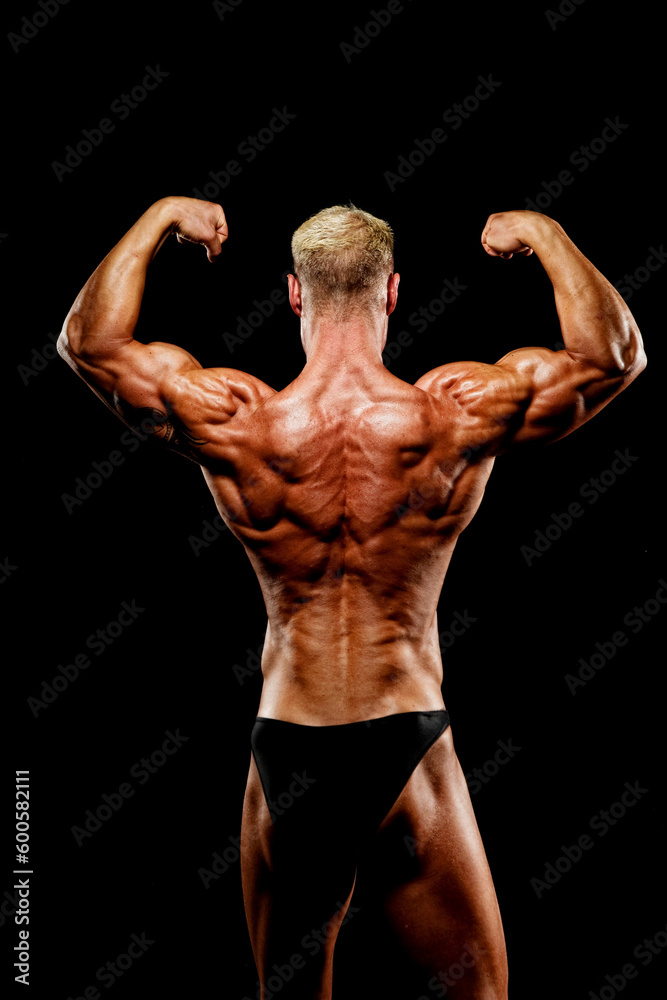 Bodybuilder Flexing Muscles against Black background Bodybuilder Flexing Muscles against Black background