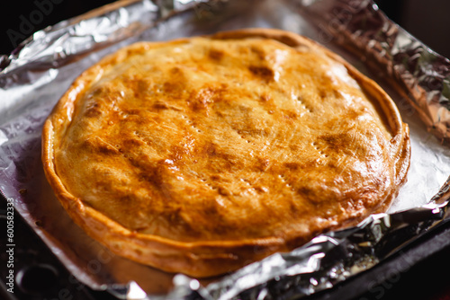 Cooked closed pie. Baked round cake on a baking sheet.