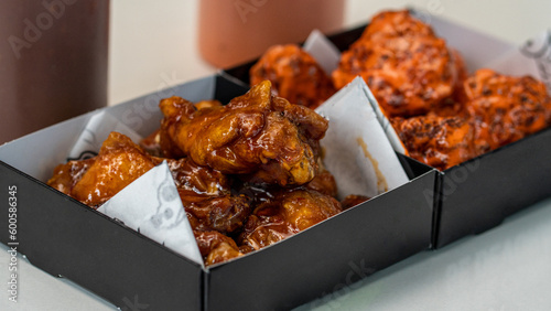 Plates of buffalo wings and wings in bbq sauce on black trays. take away food, fast food