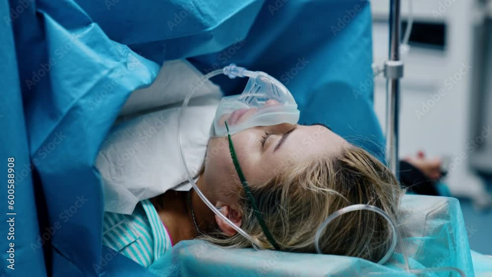Caucasian woman with oxygen mask on the operational table. Pregnant is undergoing C-section operation.