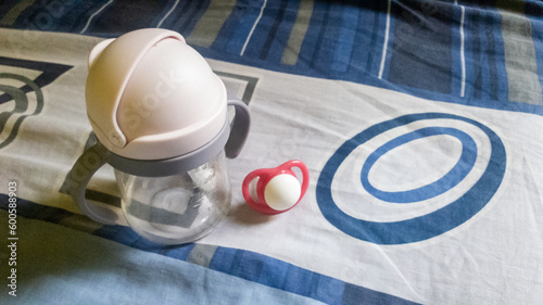 baby bottle with milk and pacifier on the bed in the bedroom