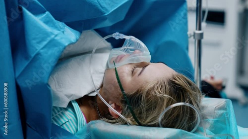 Caucasian woman with oxygen mask on the operational table. Pregnant is undergoing C-section operation.