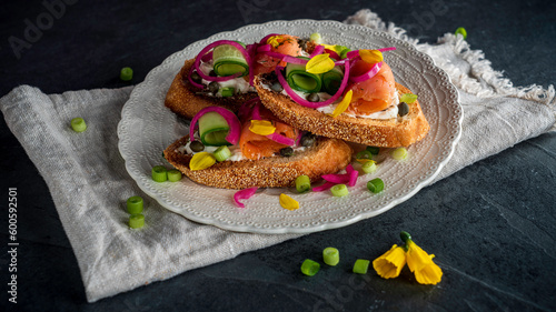 Smoked-salmon crostini with cream cheese and cucumber. Garnished with pickled red onions, scallions, and daffodil petals.