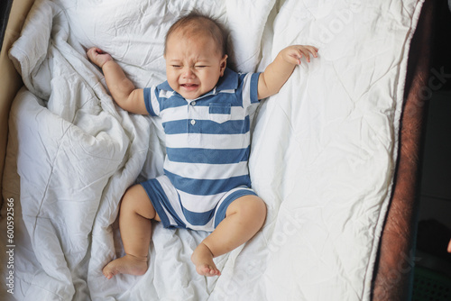 A newborn baby cries on a white sheet. Childish tantrums. Colic and abdominal pain in infants. 