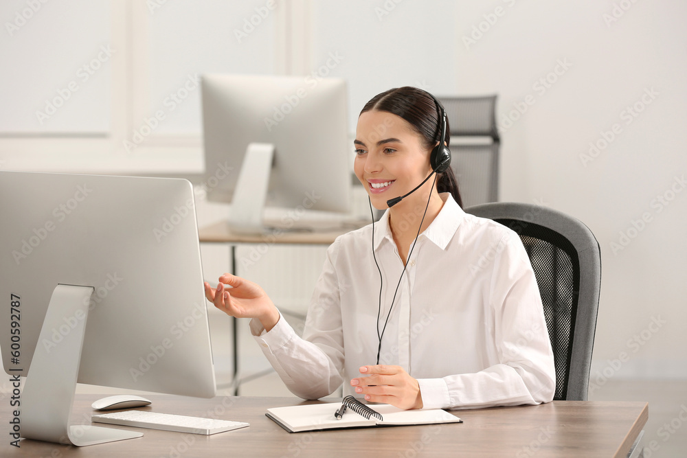 Hotline operator with headset and notebook working in office Hotline operator with headset and notebook working in office