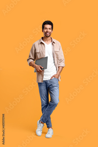 Happy man with laptop on orange background