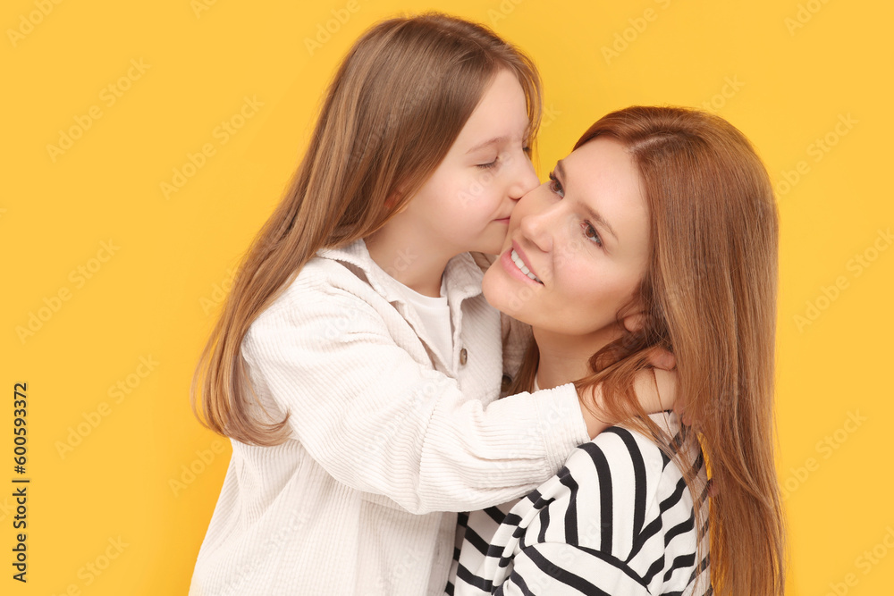 Portrait of happy mother and her cute daughter on orange background