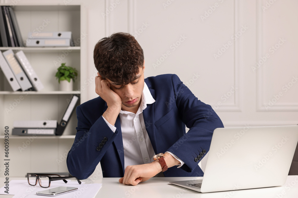 Tired young man working at table in office. Deadline concept Tired young man working at table in office. Deadline concept