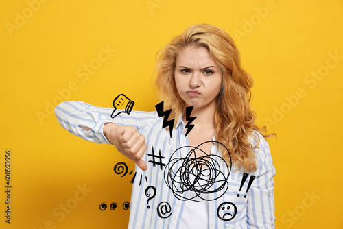 Complaint. Dissatisfied young woman showing thumb down gesture on yellow background, Different illustrations near her hand photo