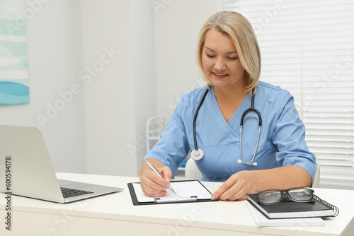 Doctor writing at white table in clinic