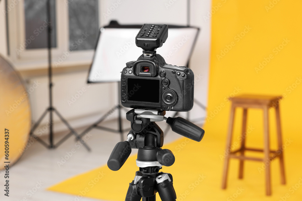 Camera on tripod, bar stool and professional lighting equipment in modern photo studio